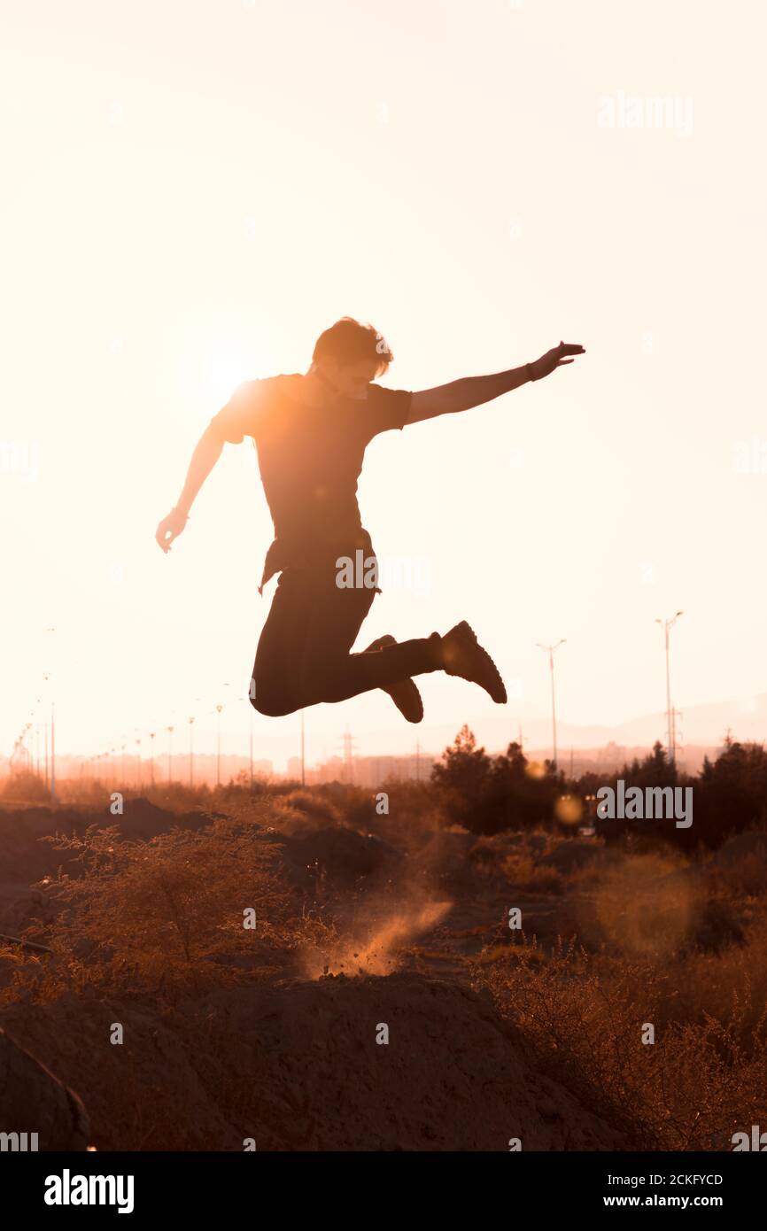 silhouette of a man jumping in a desert at sunset Stock Photo