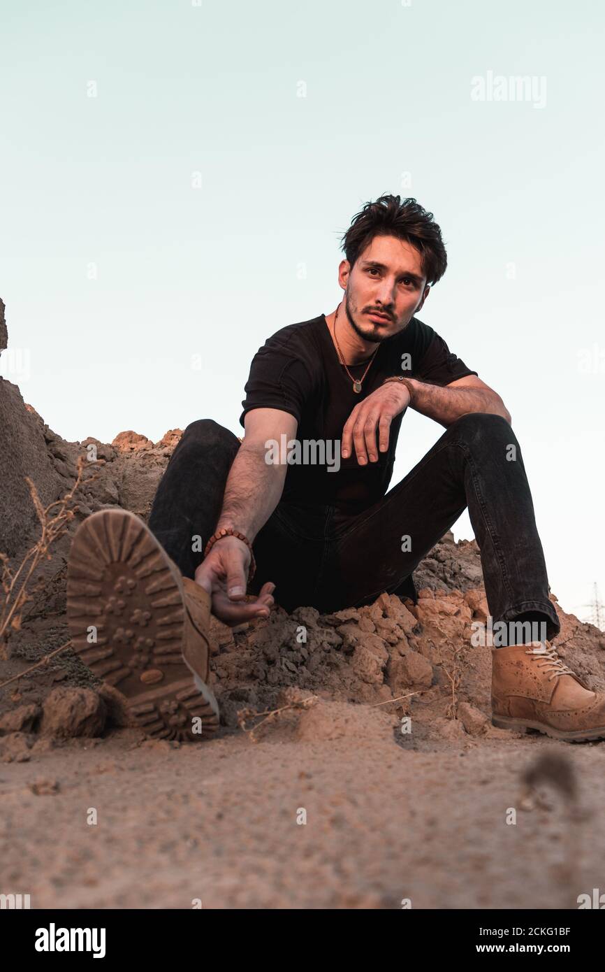 portrait of a young man in a black outfit in a desert Stock Photo