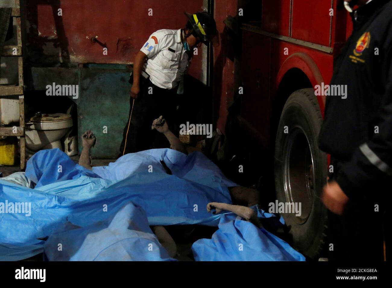 ATTENTION EDITORS - VISUALS COVERAGE OF SCENES OF INJURY OR DEATH ??A firefighter looks at the ash covered bodies of victims of Fuego volcano's eruption inside the morgue in San Juan Alotenango, Guatemala June 3, 2018. REUTERS/Luis Echeverria Stock Photo