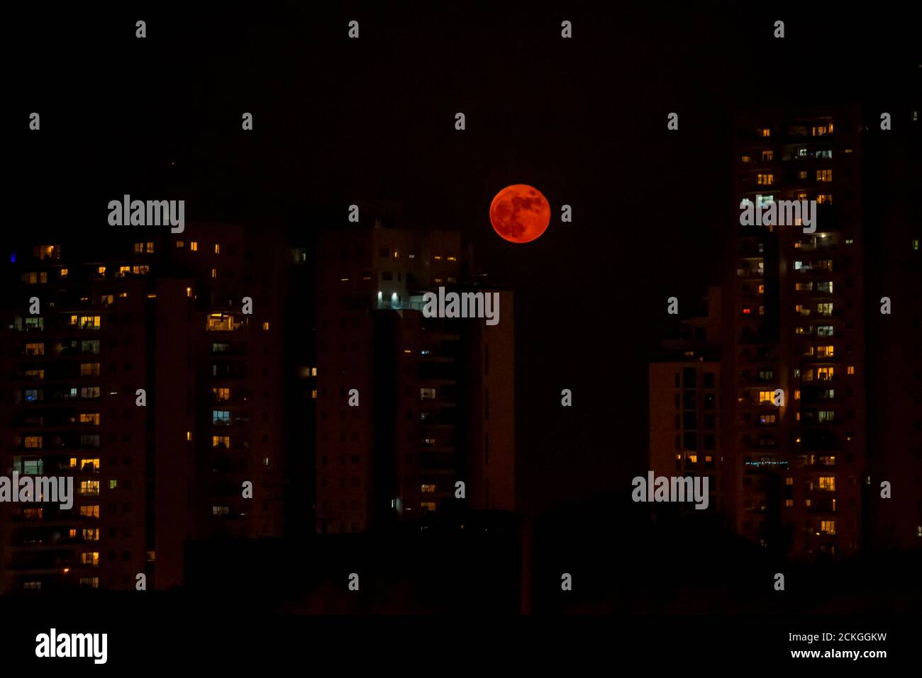 Full orange moon rises over an urban cityscape Stock Photo