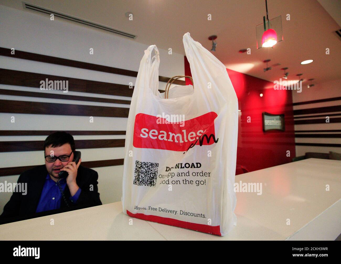 A man speaks on the phone next to a take-out bag at the reception desk at the offices of Seamless in New York January 10, 2012. Online delivery service Seamless is partnered with restaurants in over 30 major cities across the U.S. and Britain.  REUTERS/Brendan McDermid (UNITED STATES - Tags: BUSINESS FOOD) DRINK) Stock Photo