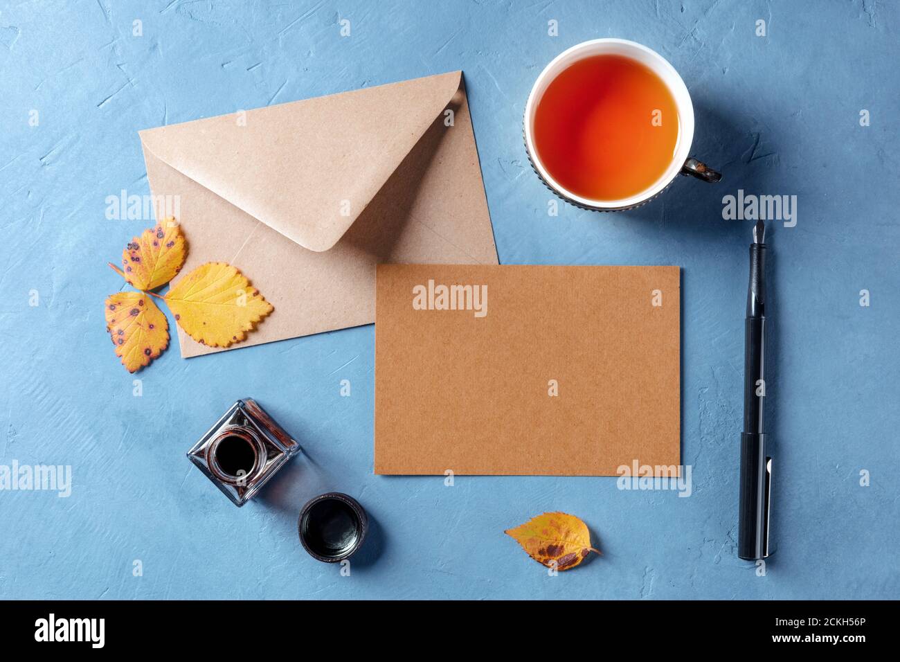 Autumn stationery mockup, a brown craft a5 card with an envelope, shot from the top with a cup of tea and ink pen, a flat lay Stock Photo
