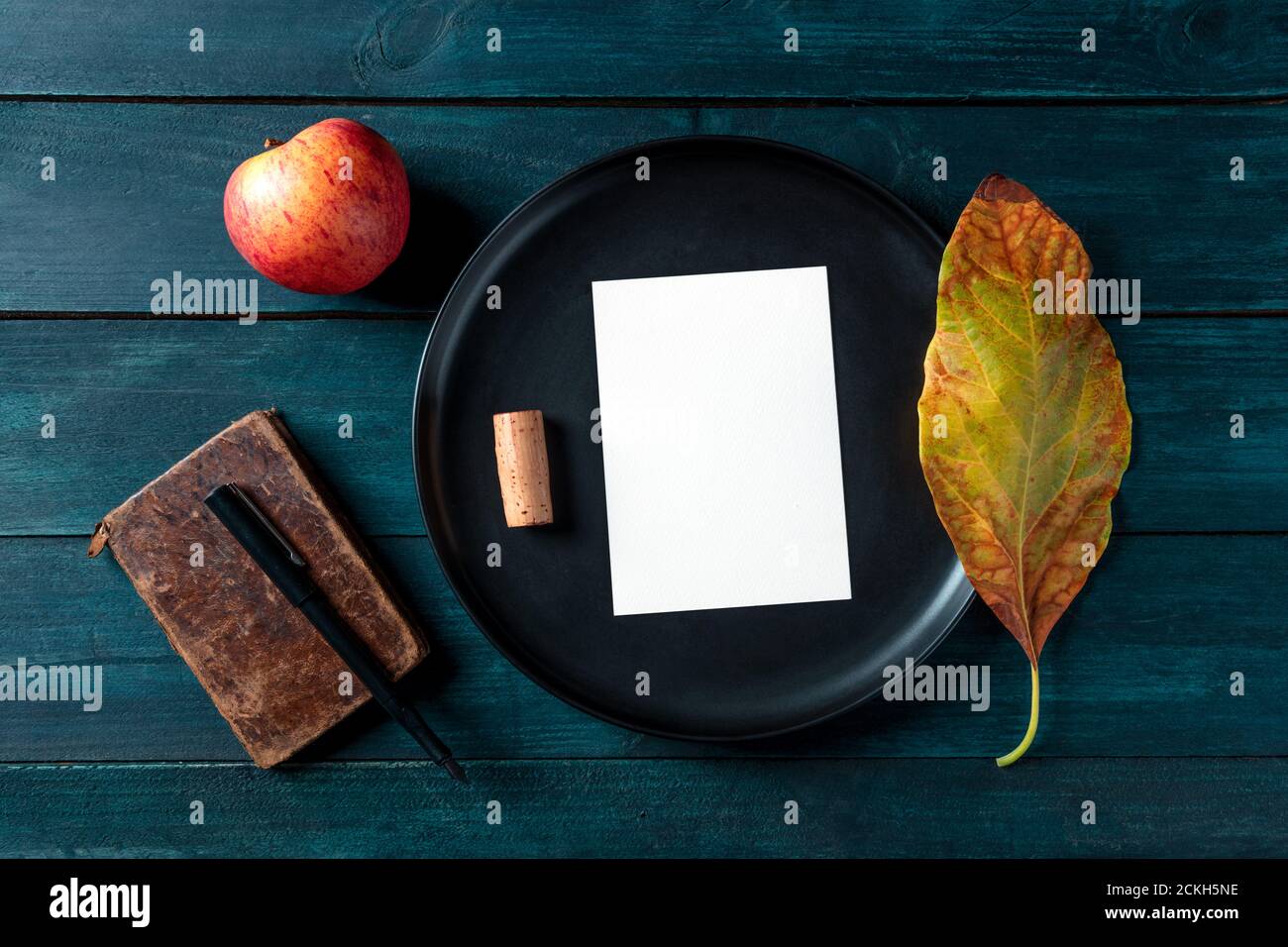 Autumn stationery mockup, a vertical A5 greeting card or invitation, shot from the top on a tray with a wine cork and an autumn leaf Stock Photo