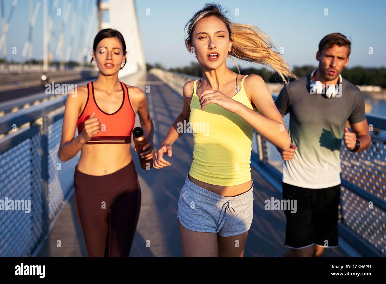 Athletic fit people exercising and running together outdoors Stock