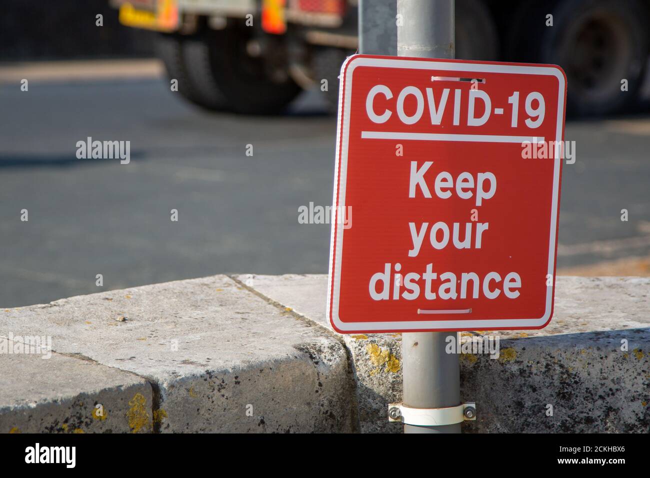 A sign reading Coviid-19 keep your distance attached to a lamppost Stock Photo