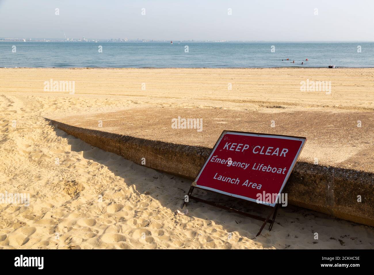 a sign at the side of a slipway on a beach with a sign saying keep clear emergency lifeboat launch area Stock Photo