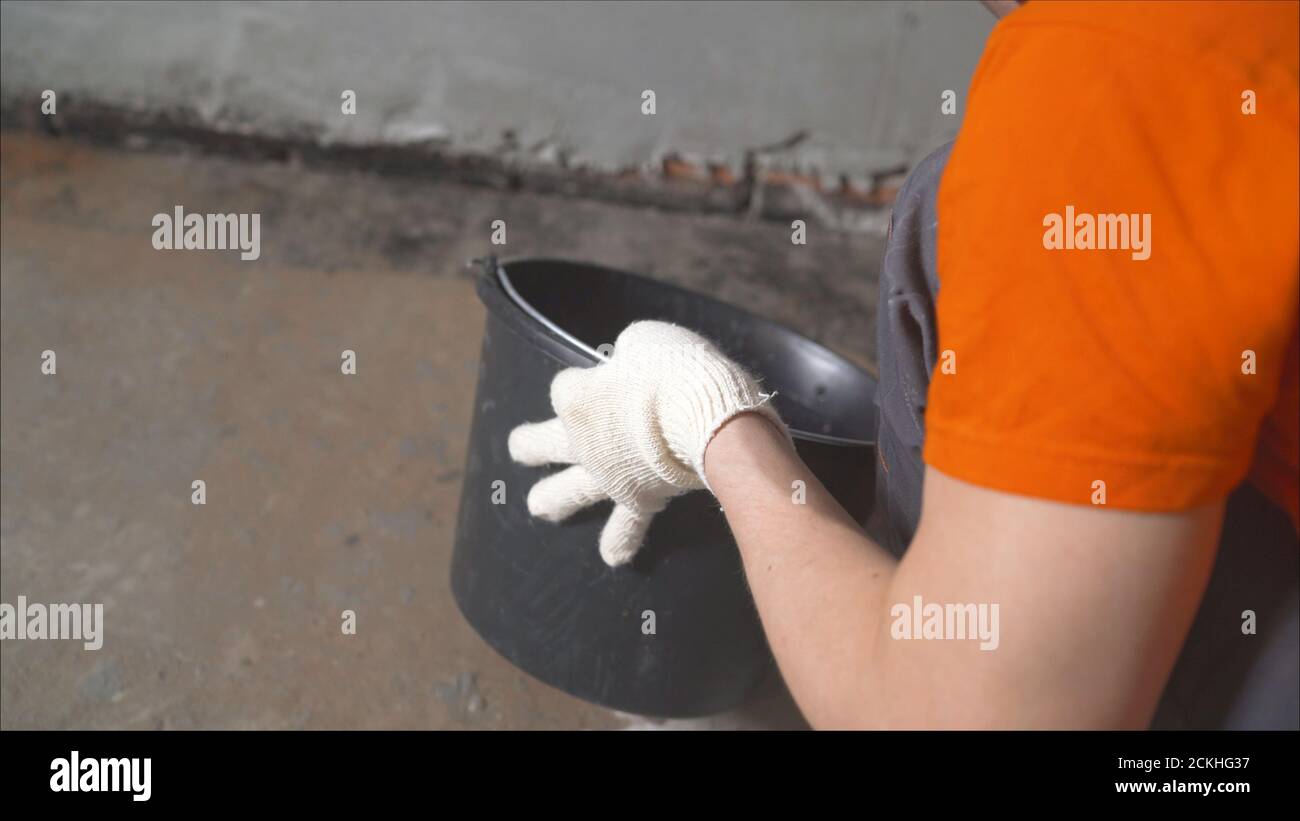 Waterproofing concrete floor with mortar and brush. An industrial worker at a construction site