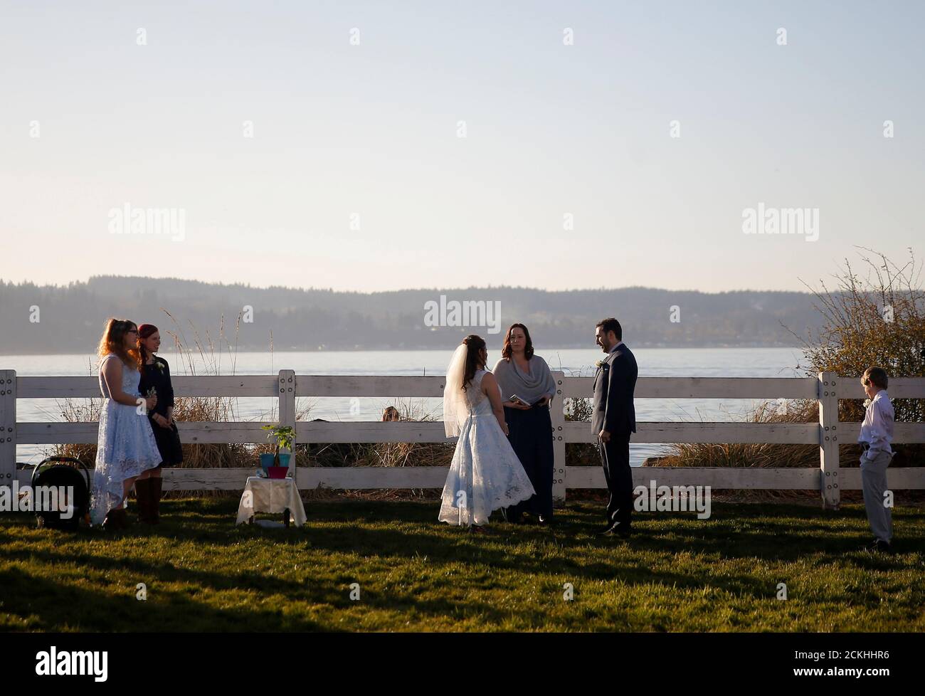 Benji Mincy and Matt Friedman listen to officiant Leah Hausman during a much smaller wedding ceremony than planned due to the outbreak of coronavirus disease (COVID-19) in Mukilteo, Washington, U.S. March 20, 2020. The couple had planned a large weekend-long wedding celebration on nearby Whidbey Island, but chose to have a small ceremony they live-streamed to those who could not come, including Mincy's mother.   REUTERS/Lindsey Wasson     TPX IMAGES OF THE DAY Stock Photo