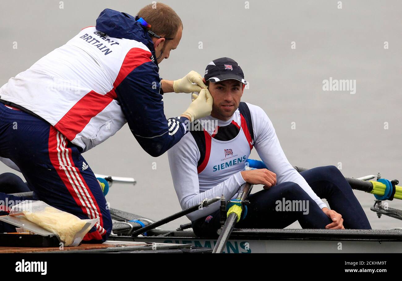 A staff member does a lactate test on British rower Mark Hunter (R) during a training session in Varese lake, northern Italy, April 18, 2012. British rowers Hunter and Zac Purchase will take part in the London 2012 Olympics in the men's double scull competition. REUTERS/Stefano Rellandini   (ITALY - Tags: SPORT ROWING OLYMPICS) Stock Photo