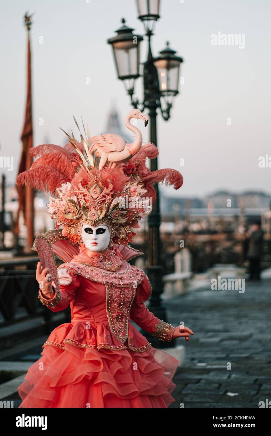 Traditional carneval costume/mask posing early morning at the waterfront during a sunrise at the annual carnival in Venice, Italy Stock Photo