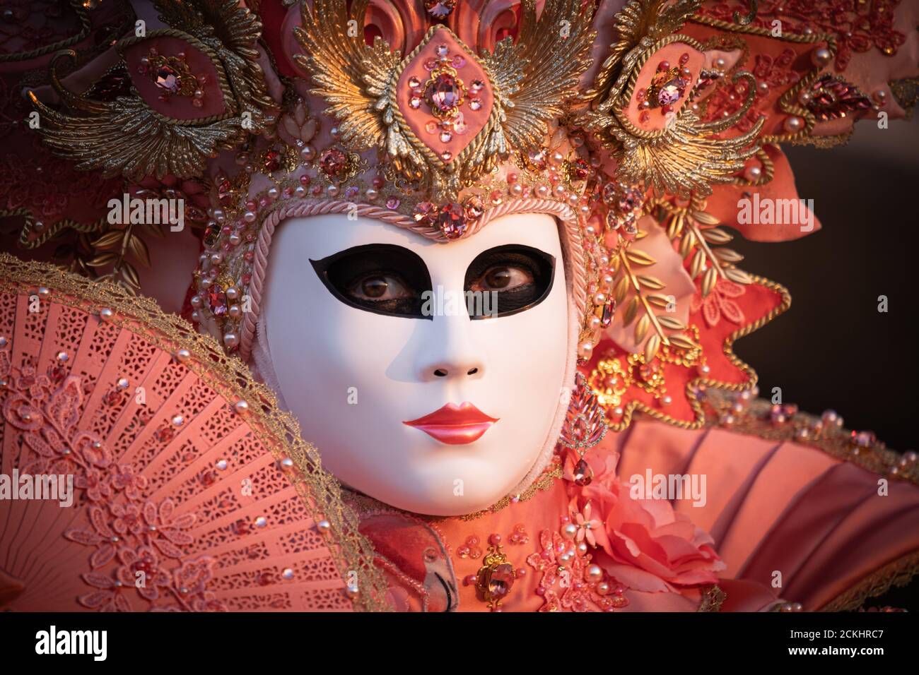 Traditional carneval costume/mask posing early morning at the waterfront during a sunrise at the annual carnival in Venice, Italy Stock Photo