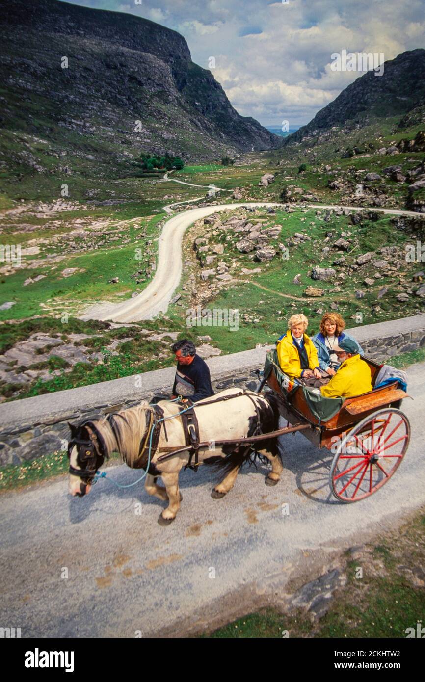 A traditional pony and trap traverses the Gap of Dunloe in Killarney with tourists, Ireland. Stock Photo