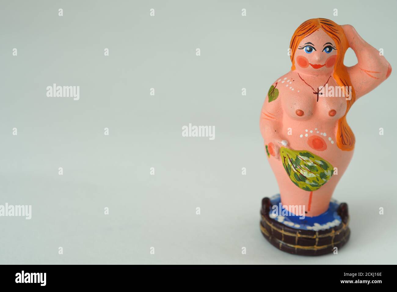 Funny figurine of ceramics, plaster and clay. A woman in a bath with a broom. Stock Photo