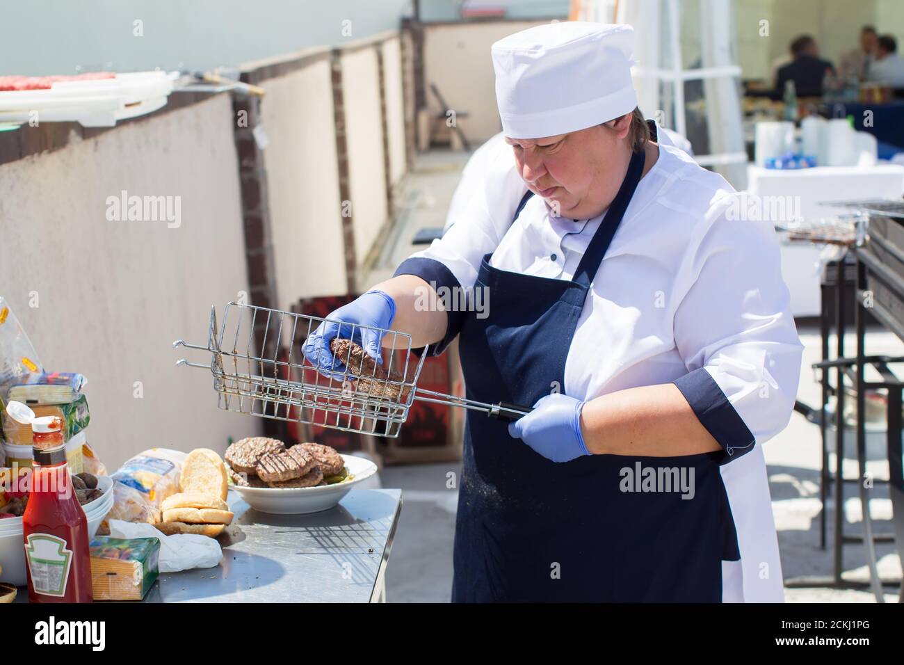 Belarus, Gomel district on July 17, 2020. The streets of the city. Woman cook on the street prepares a hamburger. Stock Photo