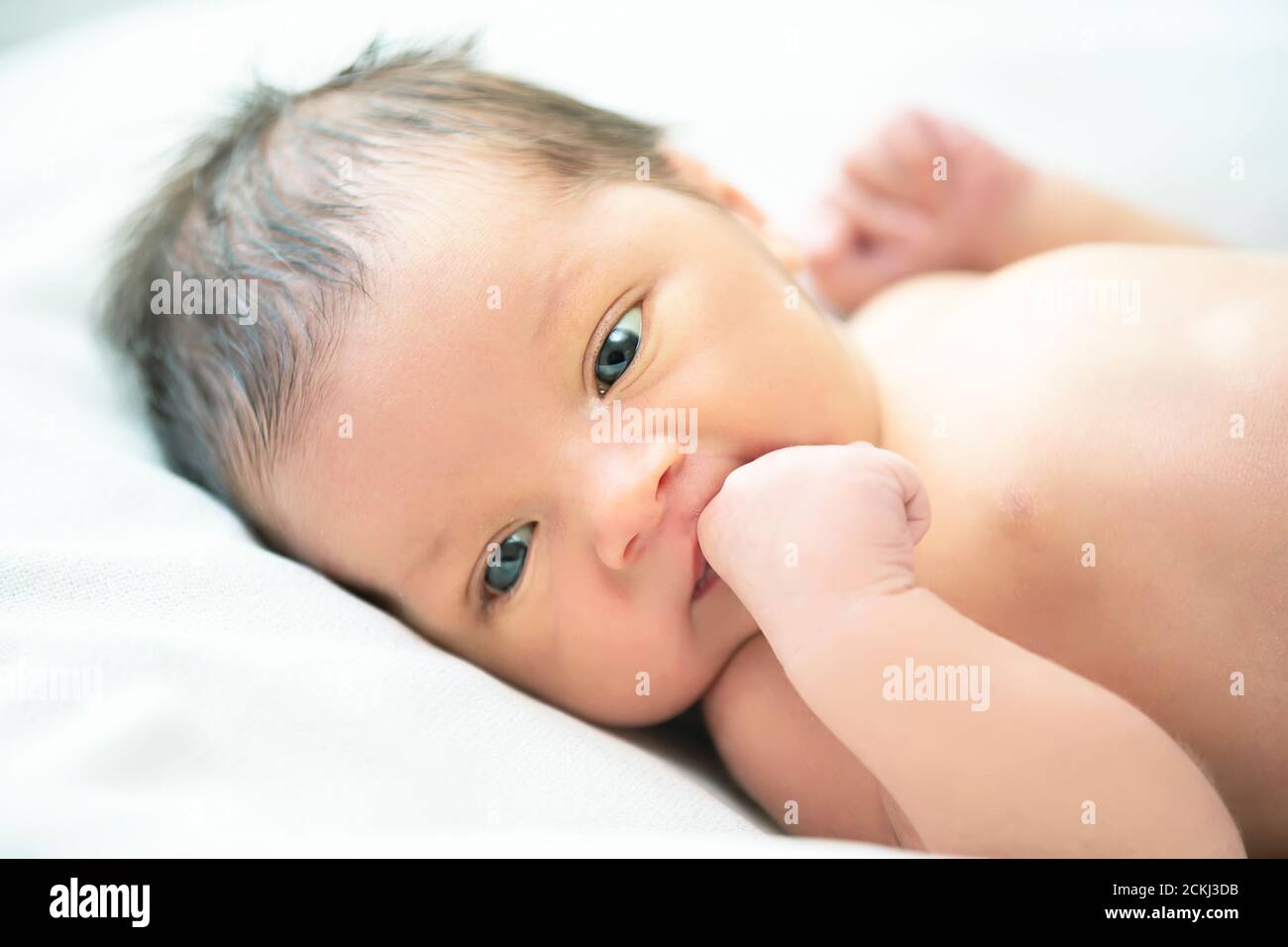 Newborn baby with open eyes sucks on a cam Stock Photo Alamy