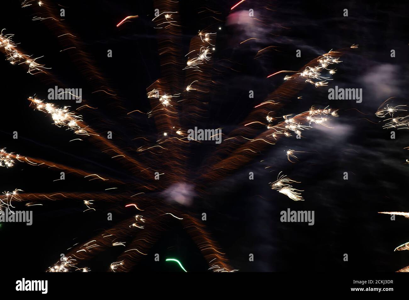 Light spots of fireworks of golden color on a long exposure on a black background. Festive background. Stock Photo