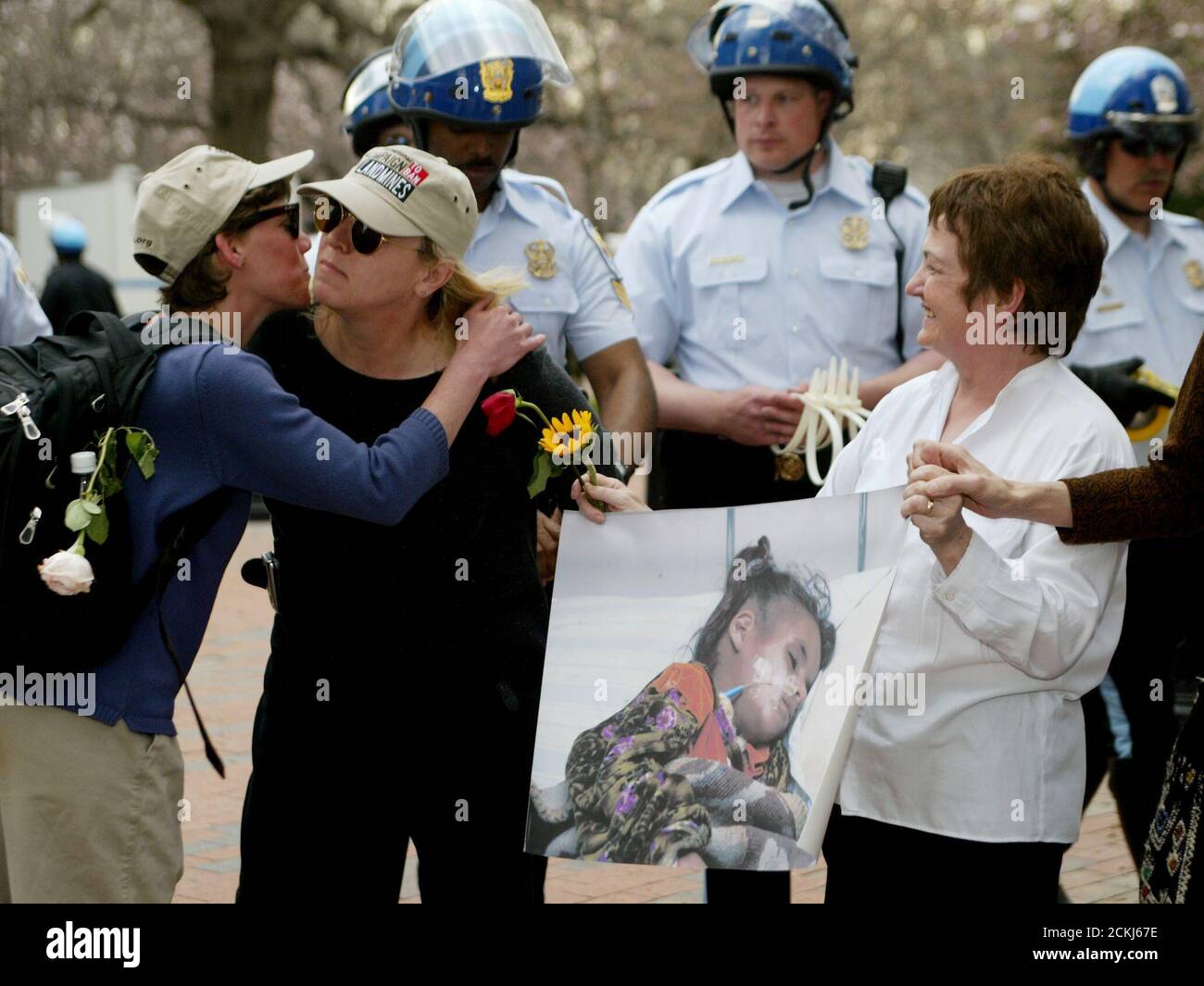 Nobel Peace Prize laureate and International Campaign to Ban Landmines founder Jody Williams (C) gets a hug from ICBL coordinator Elizabeth Bernstein (L) as U.S. Park police officers cuff her hands behind her back and arrest her, in front of the White House in Washington March 26, 2003. Fellow Nobel Peace Prize laureate from Northern Ireland Mairead Corrigan Maguire waits to be arrested. The Nobel winners were joining in a non-violent civil disobedience action organized by religious leaders to protest the war in Iraq. REUTERS/Jim Bourg  JRB/GN Stock Photo