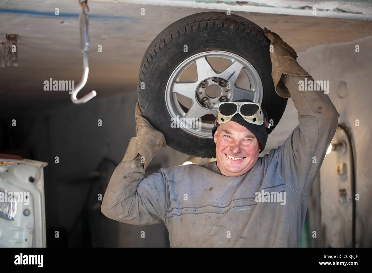 Male auto mechanic in a garage with a car wheel.Fitting tires Stock ...