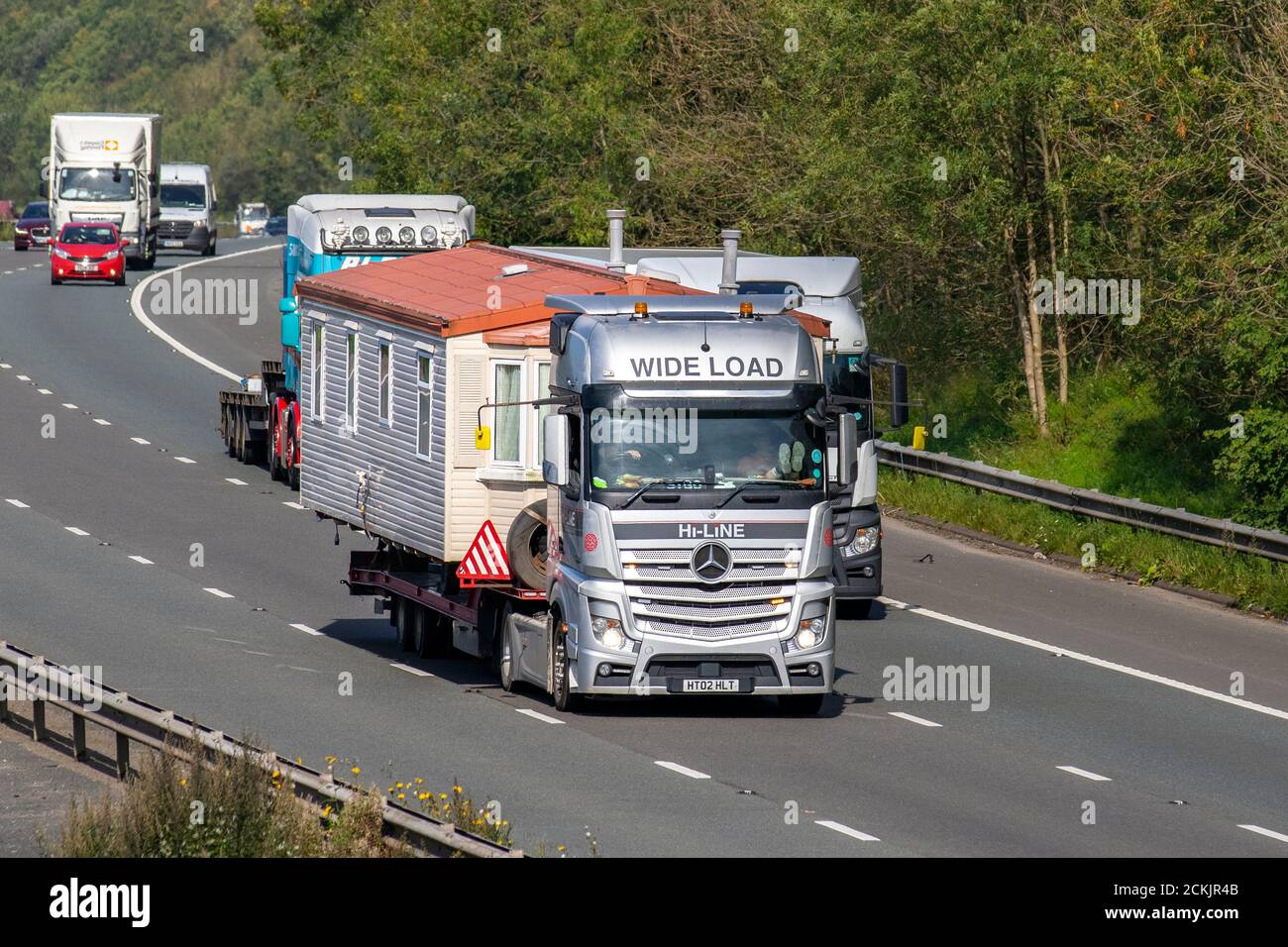 Mobile Home wide load haulage delivery trucks overtaking vehicles, lorry, transportation, Mercedes Benz truck, cargo, Scania R420 vehicle, static caravans delivery, commercial transport, industry, supply chain freight, on the M6 at Lancaster, UK Stock Photo