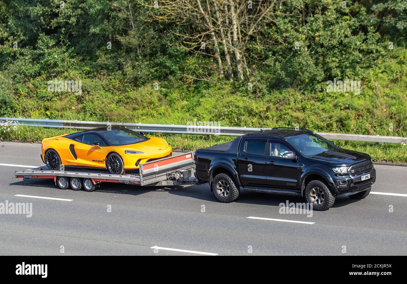 Yellow McLaren GT Manchester supercar; Vehicular traffic moving