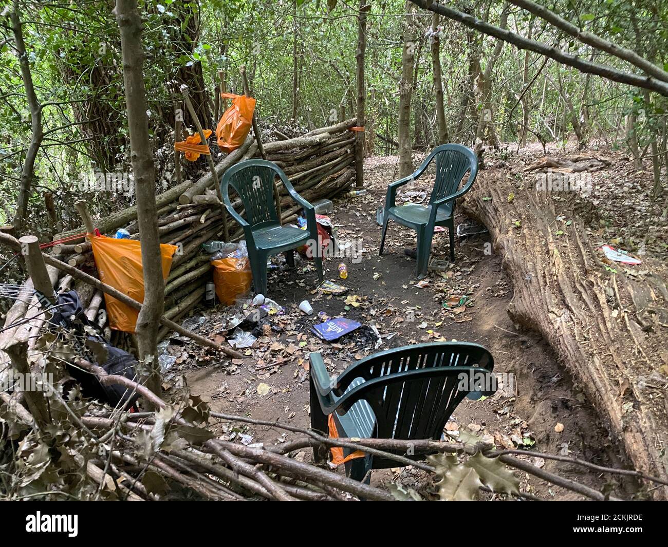 A drug, glue sniffing and alcohol den in woodland near Godalming in Surrey, England. Plastic bags of discarded beer and glue tins litter the countrysi Stock Photo