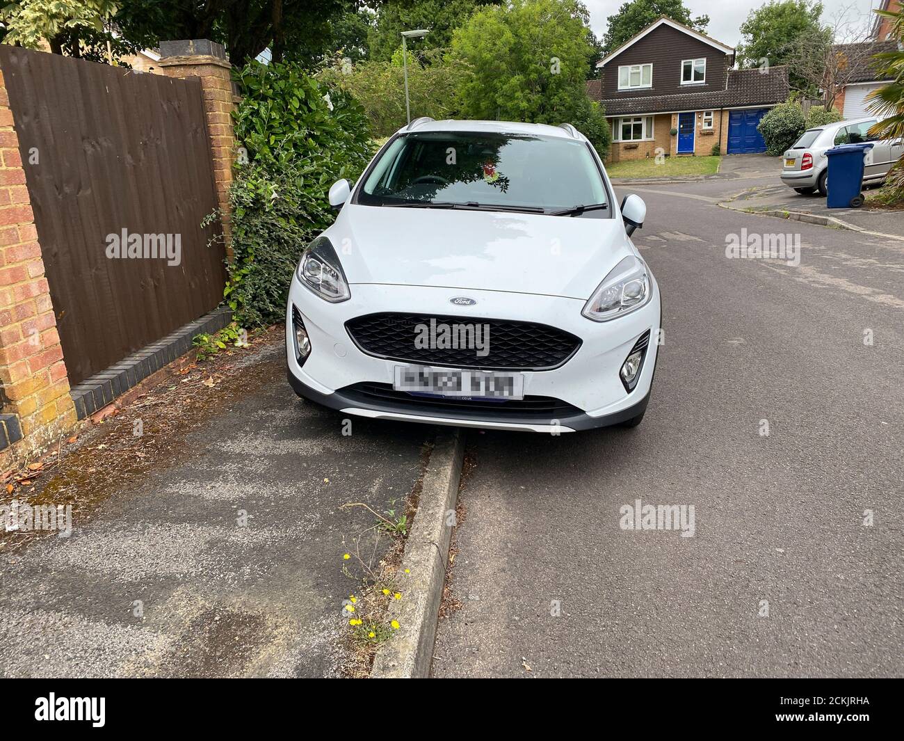 A car parked on a pavement in Surrey, England. The blocking of pavements for pedestrians has become an increasing problem in the United Kingdom and pl Stock Photo