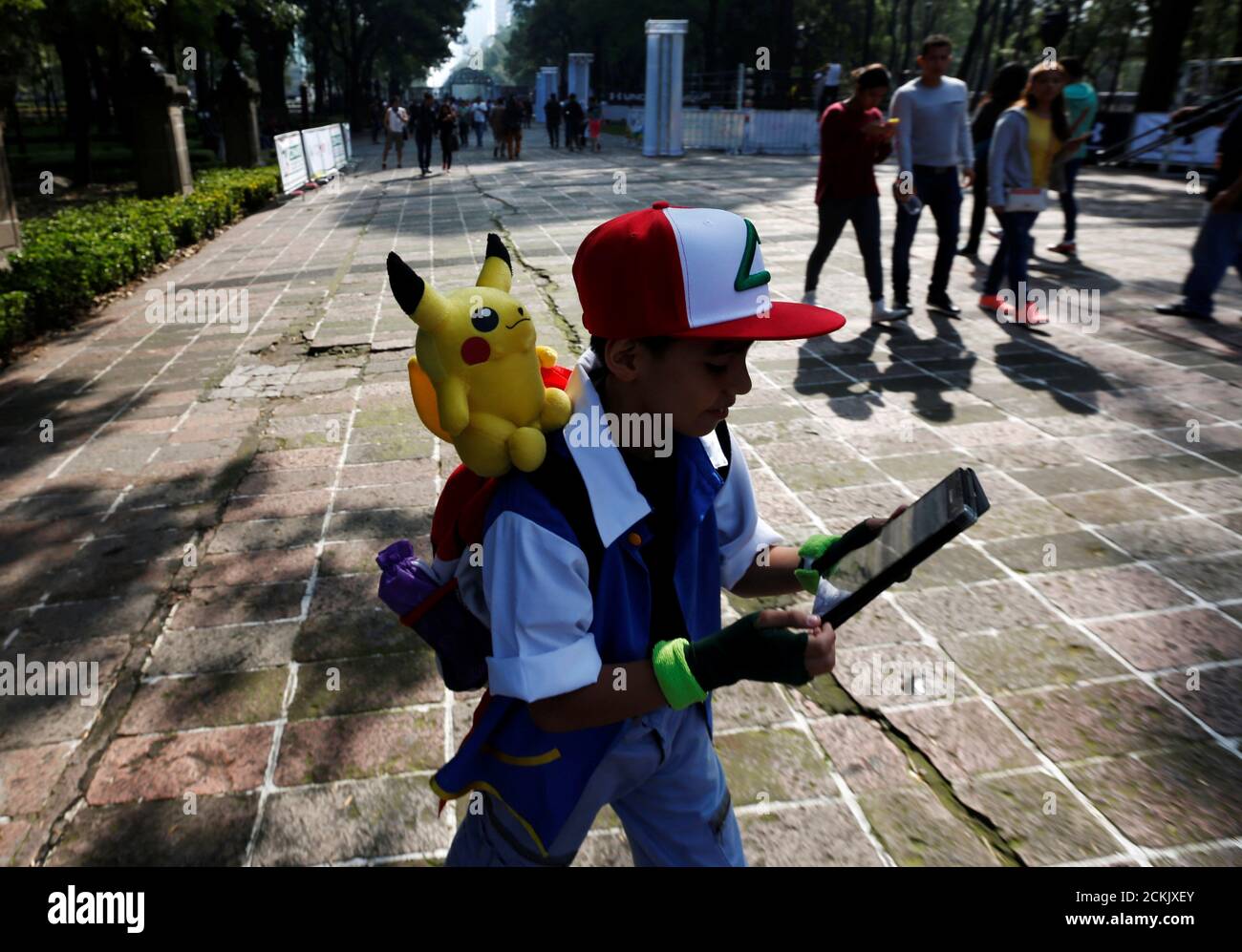 A child carries a Pokemon character, Pikachu, on his shoulder as he plays  Pokemon Go during