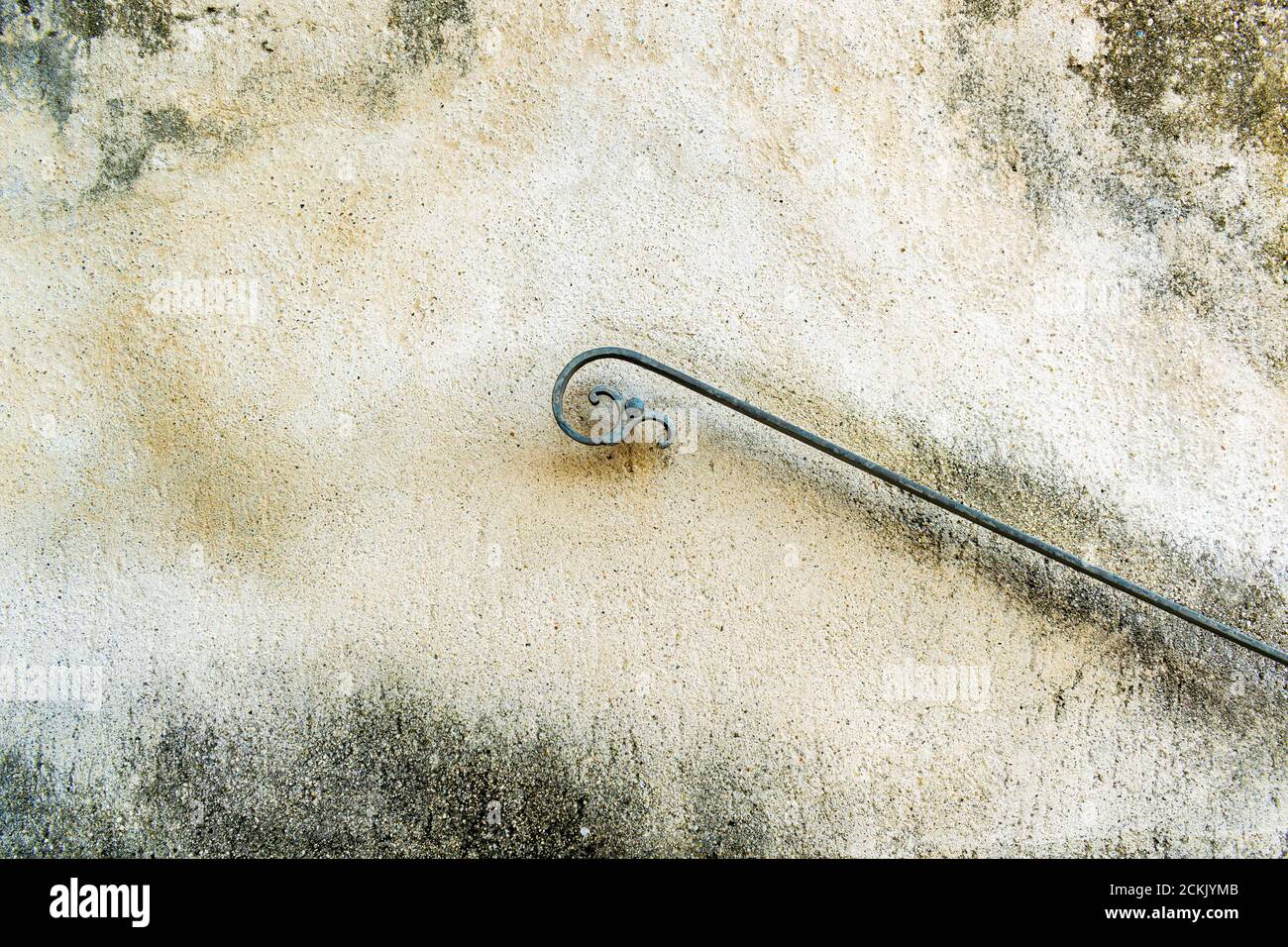 Weathered wall exterior with detail of old wrought iron handrail with the stylized shape of a flying person Stock Photo