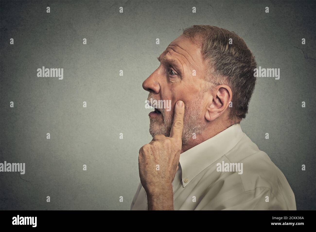 Portrait worried man thinking looking up isolated on grey wall background with copy space. Human face expressions, emotions, feelings, body language, Stock Photo
