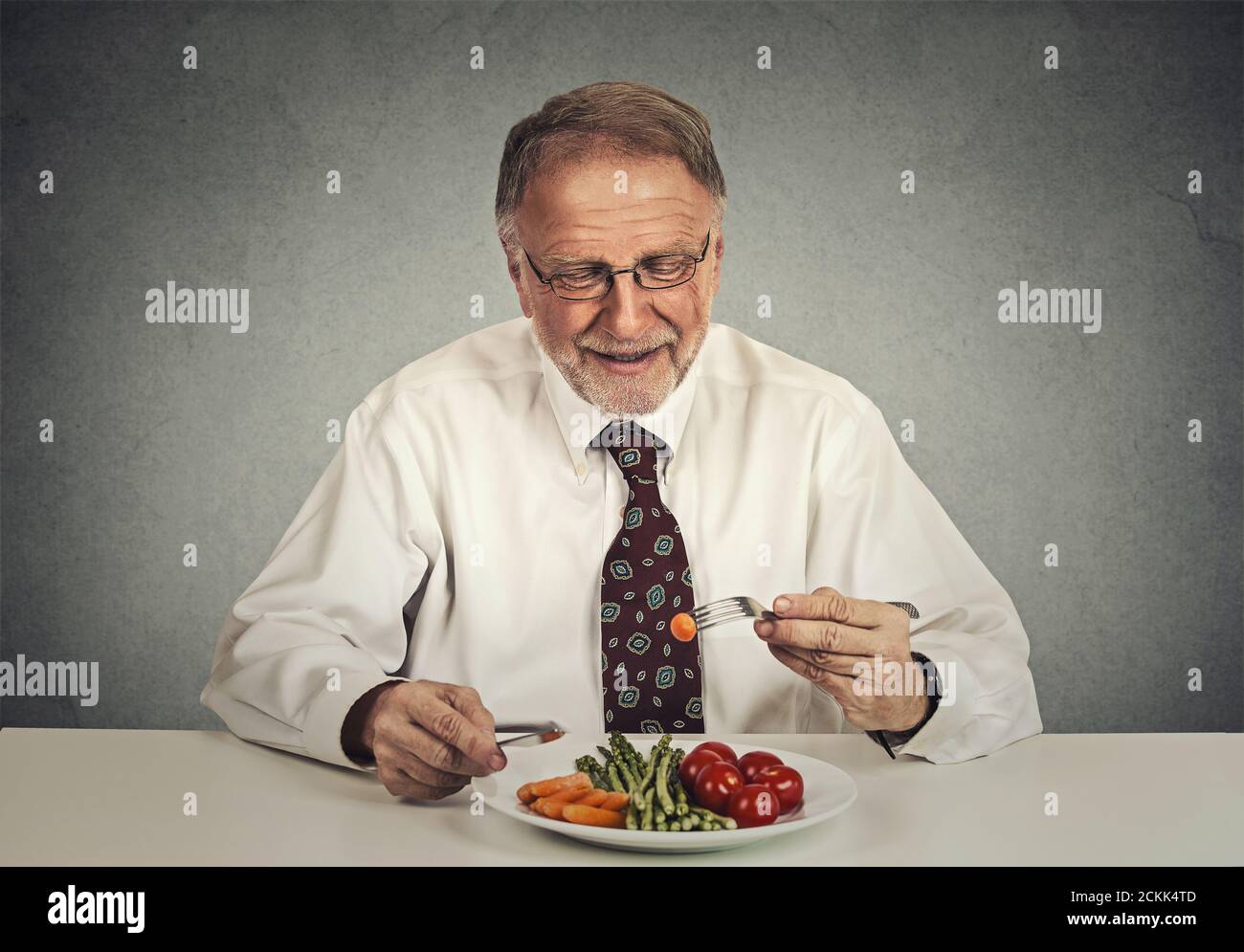 Happy senior man eating fresh vegetable salad Stock Photo