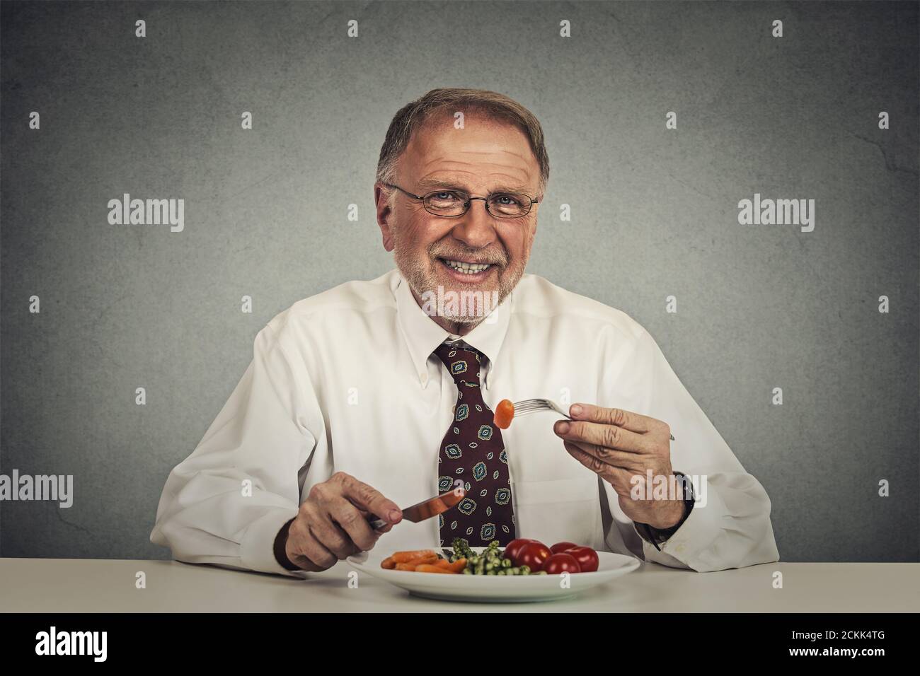 Happy senior man eating fresh vegetable salad Stock Photo