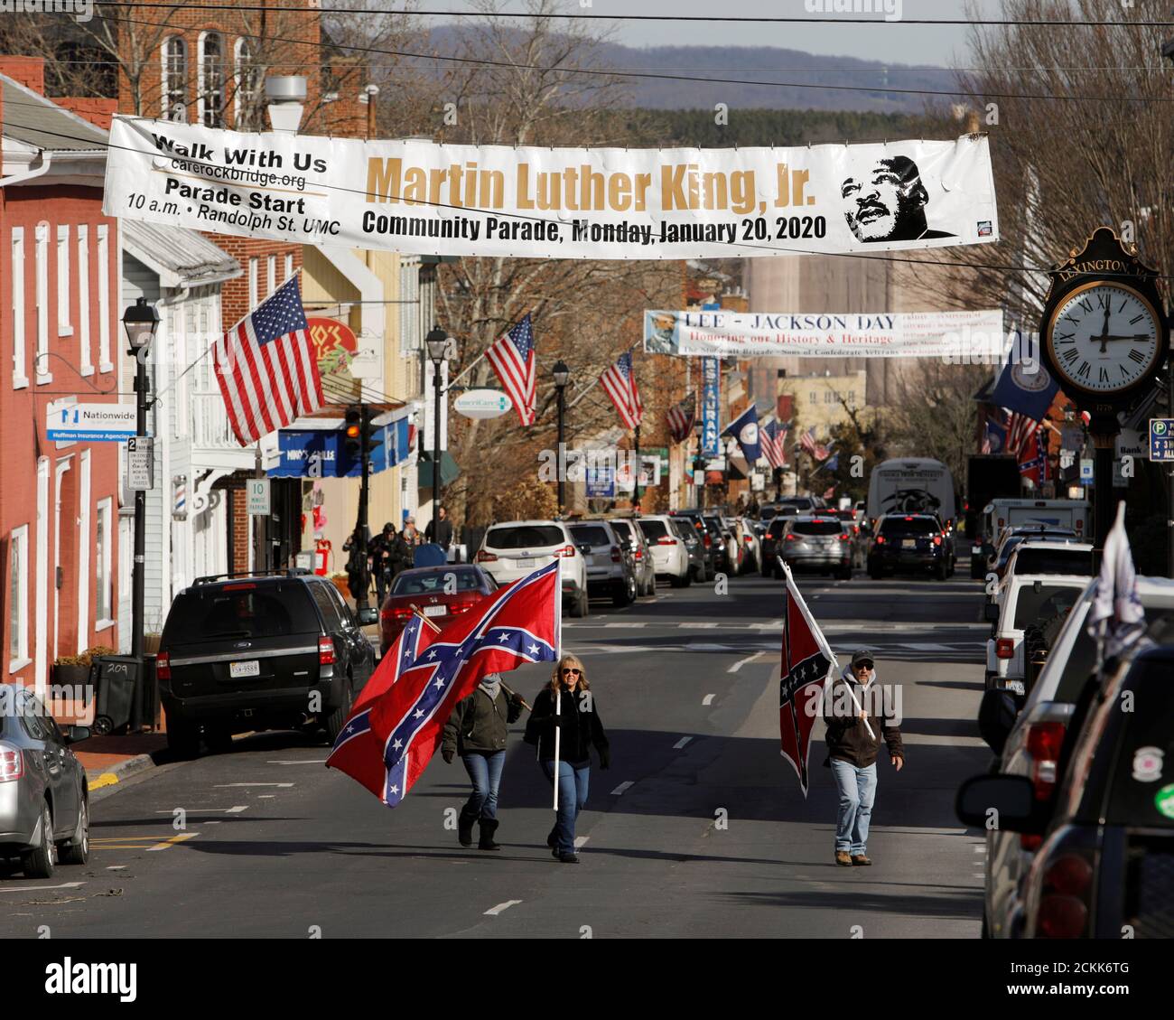 Supporters of Confederate statues and symbols carry Confederate flags as  they walk under a sign commemorating the upcoming Martin Luther King Jr. Day,  during the Lee-Jackson Day state holiday in Lexington, Virginia,