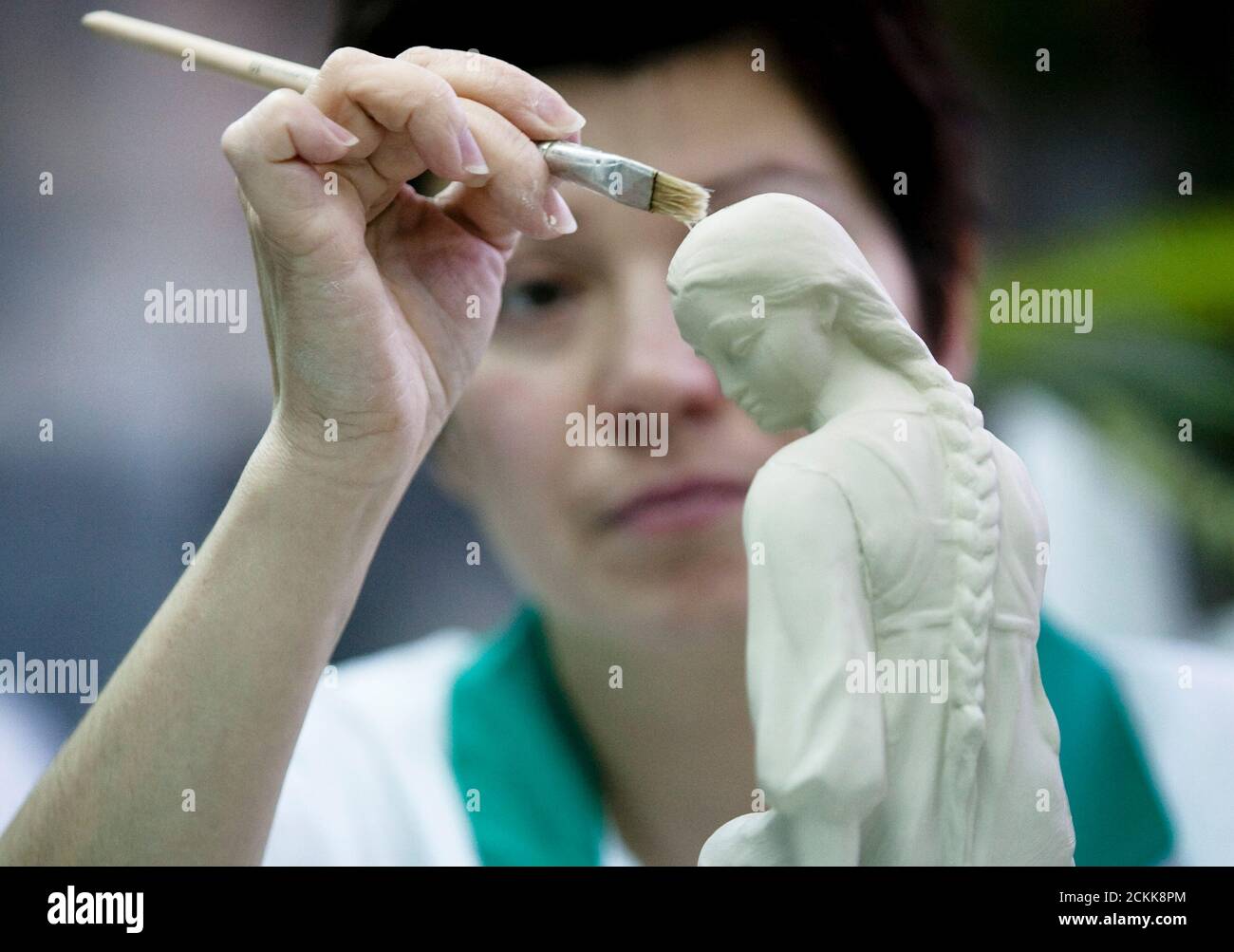 A woman wets the surface of a clay figure that is to be used to cast porcelain sculptures in the Dulevo Porcelain factory in the town of Dulevo, 115 km (73 miles) from Moscow February 20, 2009. A Tsarist-era porcelain factory that survived the Russian revolution and the end of the Soviet Union is on the verge of collapse, its plight typical of hundreds of outmoded industrial plants across this vast country. Founded in 1832, the Dulevo Porcelain pottery once supplied the Russian court. In the 20th century, it produced special communist revolutionary pieces for the Bolshevik elite and their alli Stock Photo
