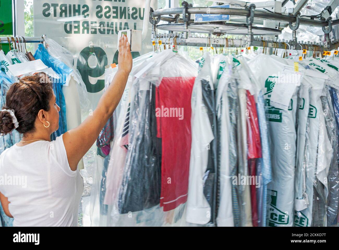 Miami Florida,Hispanic woman female worker working employee job staff launderer dry cleaner cleaners dry cleaning inside interior dry cleaned clothes Stock Photo