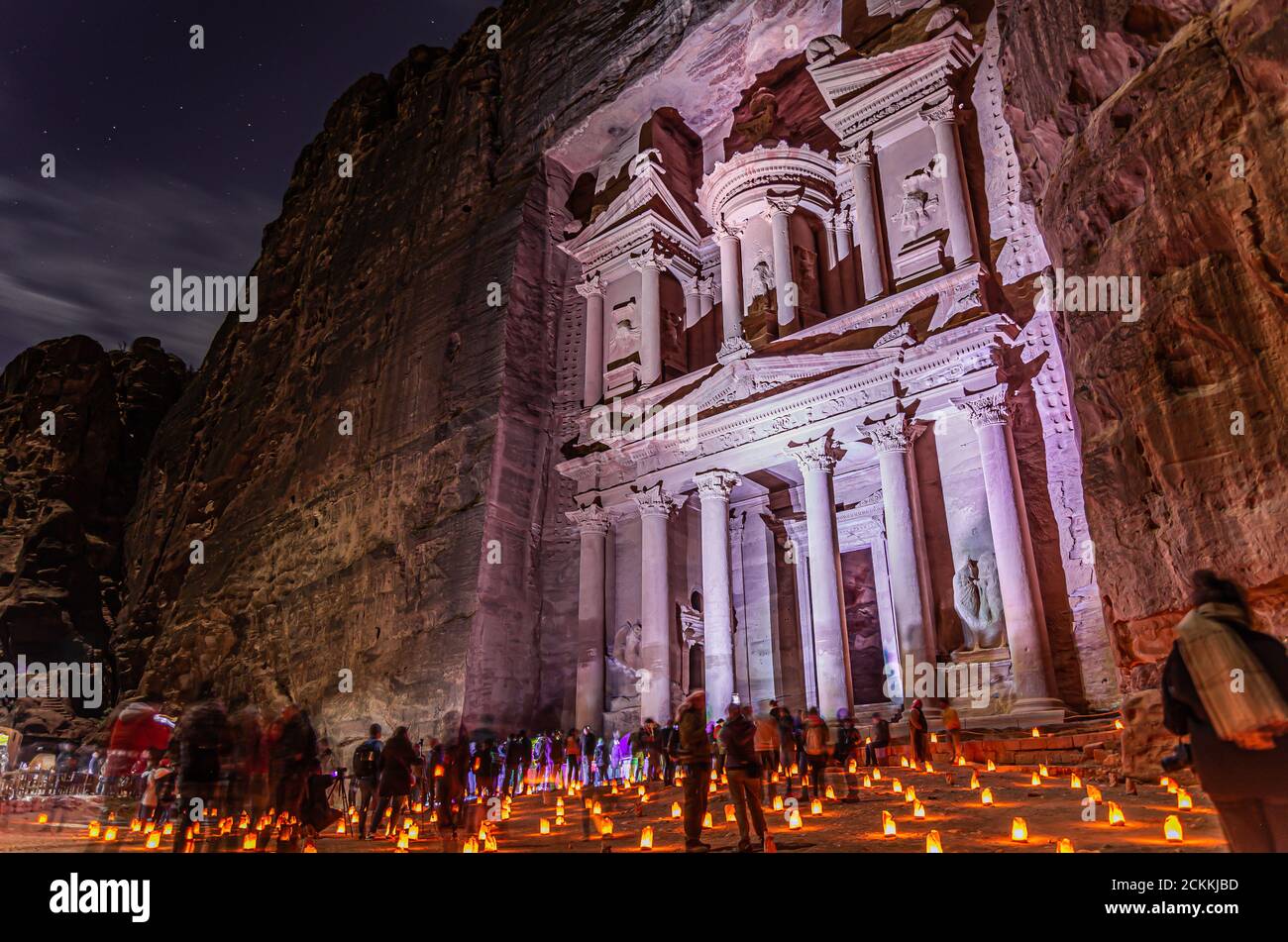 Night photography of the ancient city of Petra, world heritage site UNESCO, The Treasure of Petra illuminated with purple light and floor with candles. Stock Photo