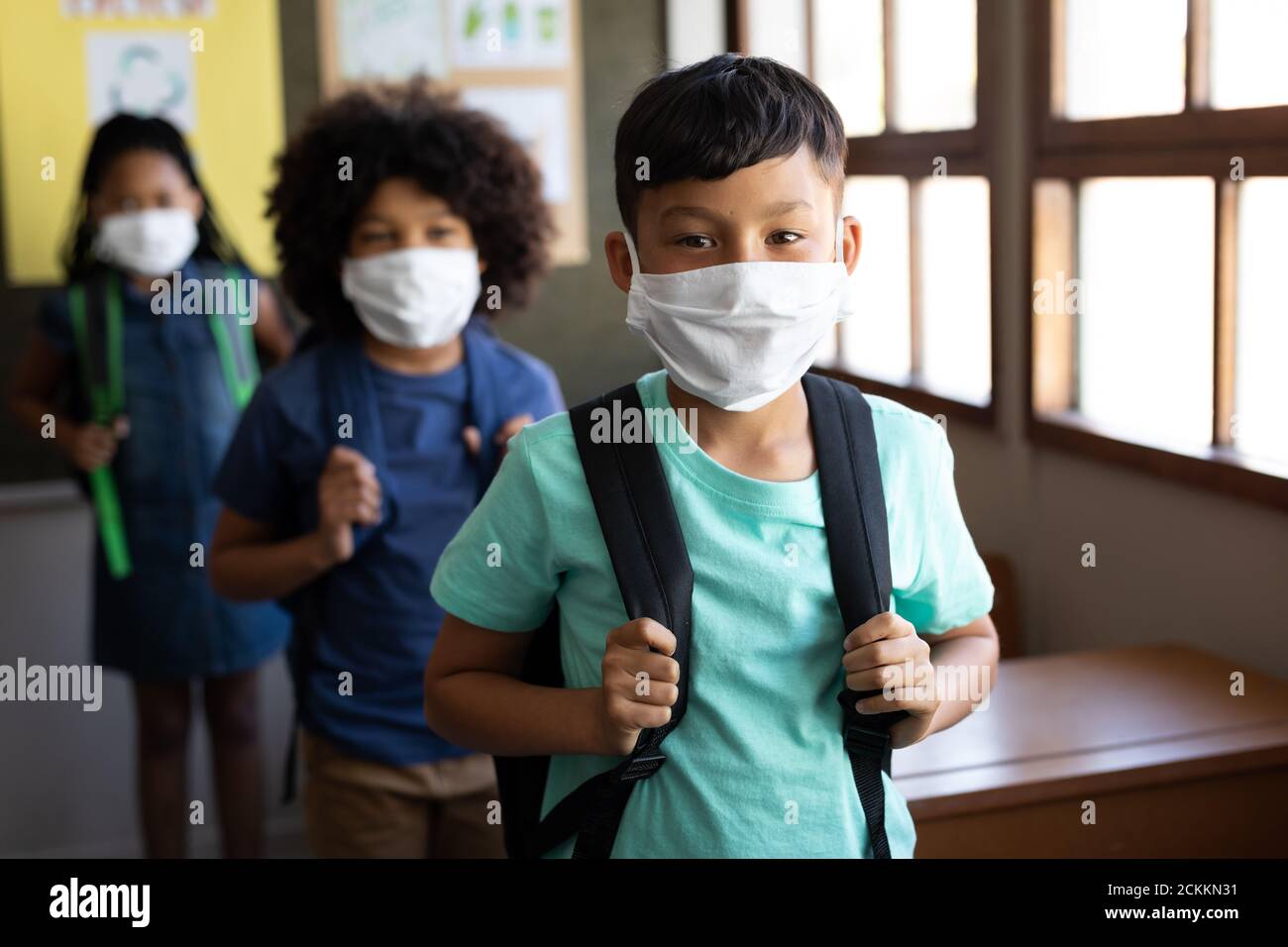Group of kids wearing face masks with bag packs standing in a queue at school Stock Photo