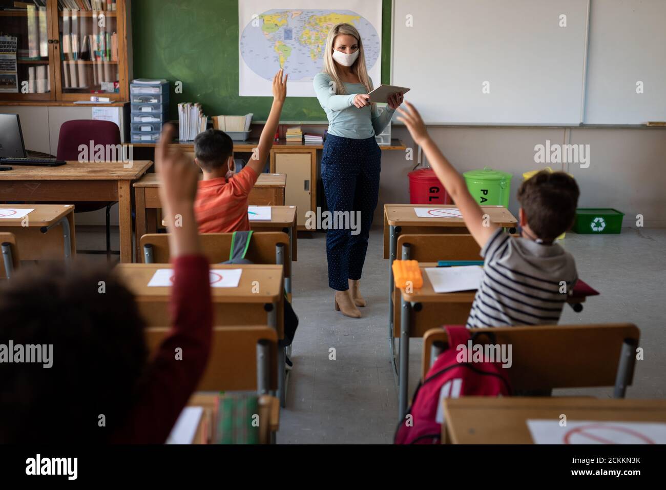 Rear view of boy raising his hand in the class at school Stock Photo