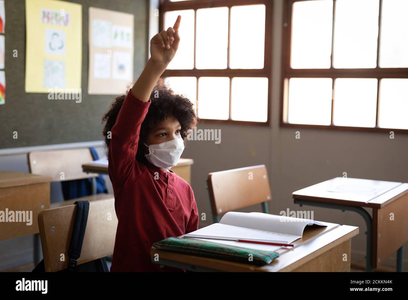 Boy raising his hand in the class at school Stock Photo