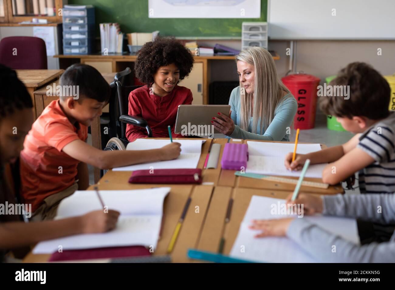 Female teacher with digital tablet teaching a disable boy in wheel chair at school Stock Photo