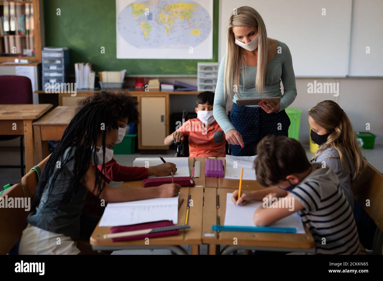 Female teacher wearing face mask teaching in class at school Stock