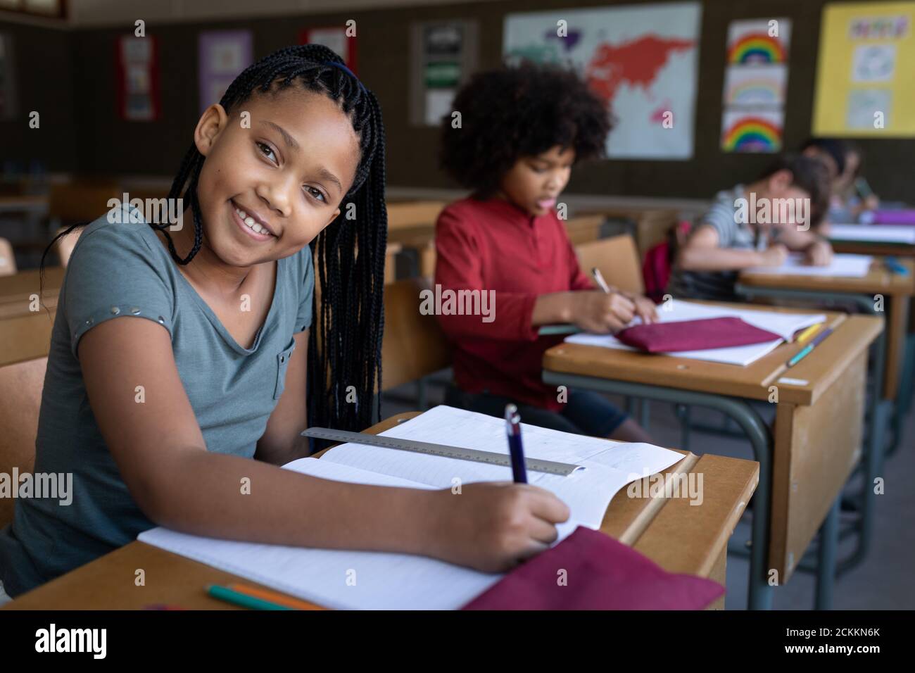 Portrait of girl smiling while sitting on her desk at school Stock Photo