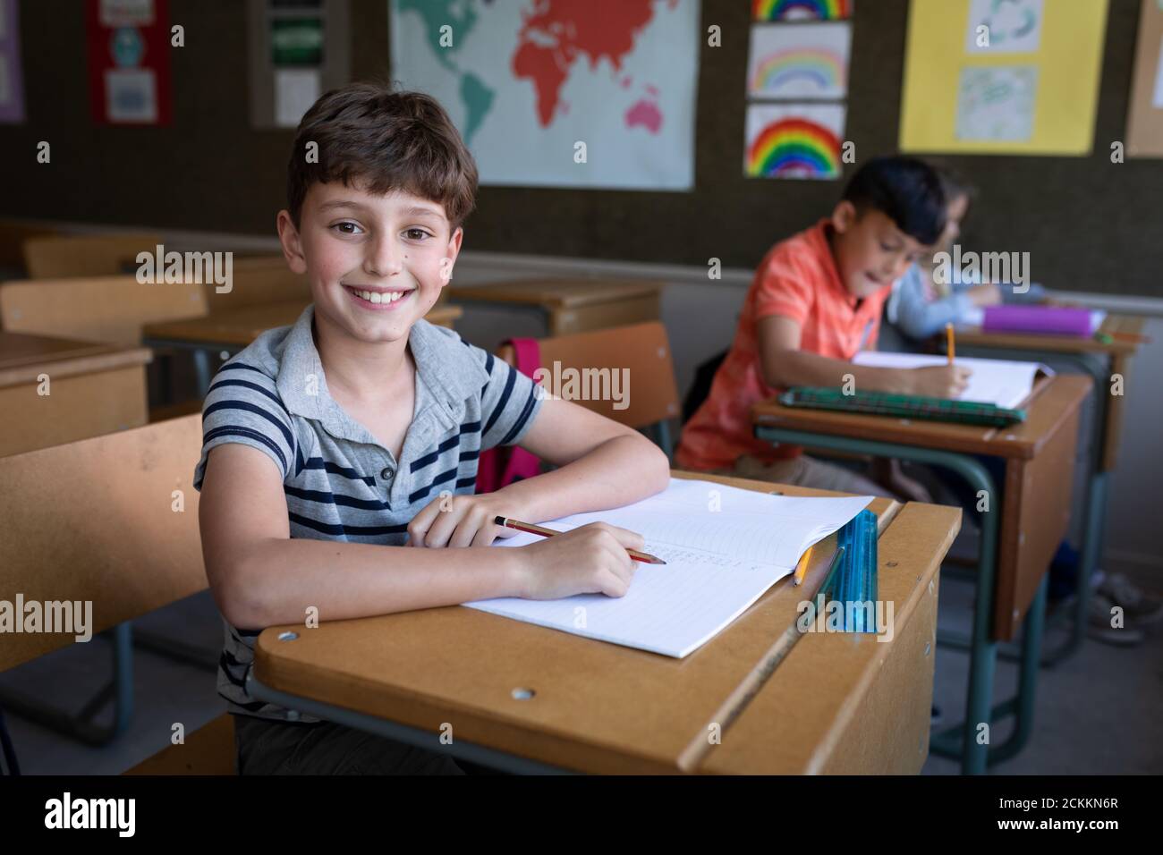 Portrait of boy smiling while sitting on his desk at school Stock Photo