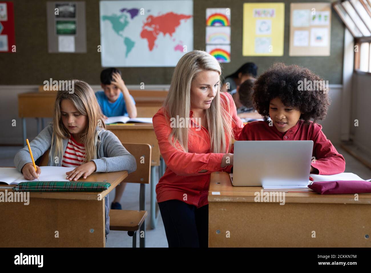 Female teacher and boy using laptop in class at school Stock Photo