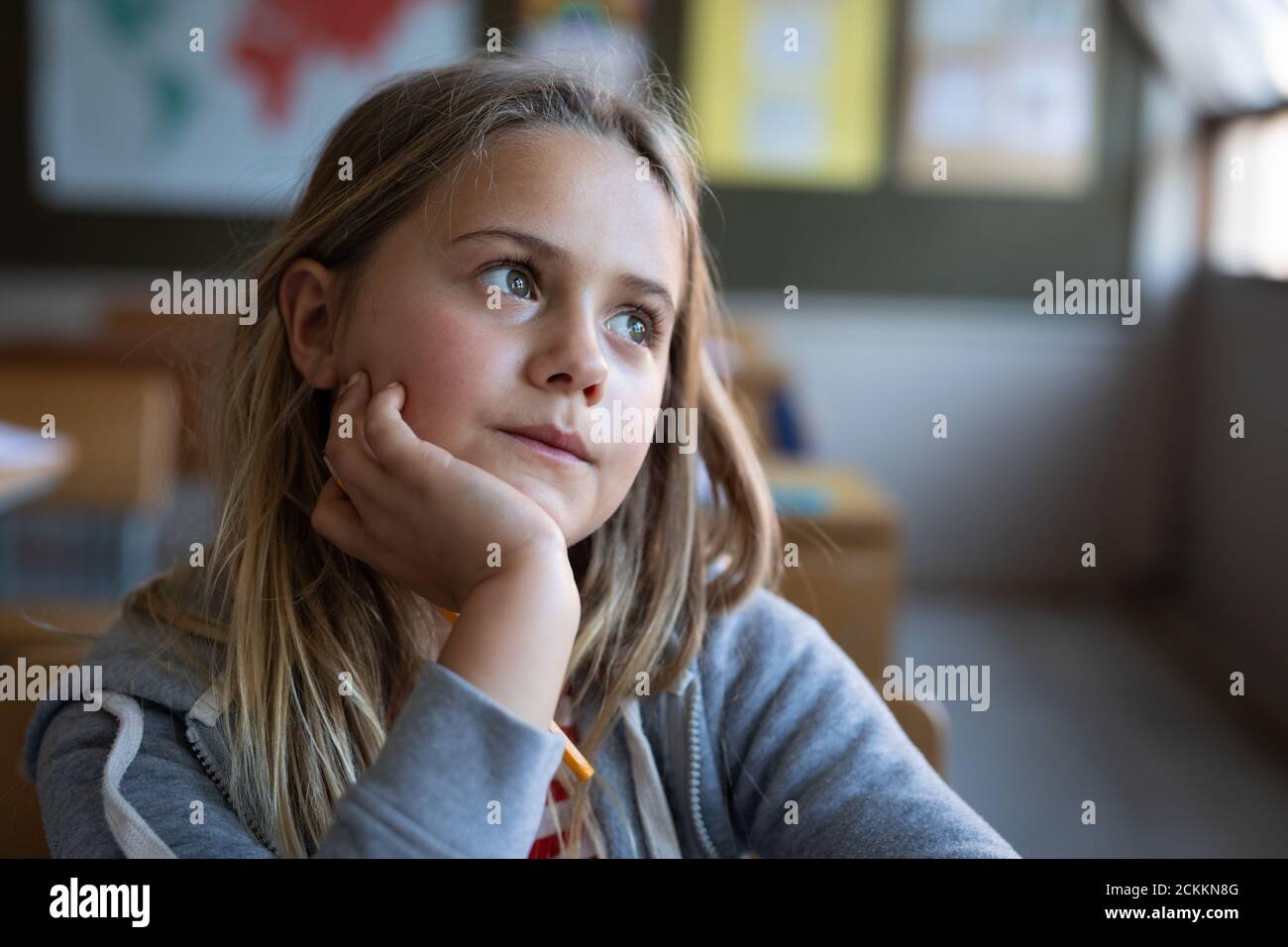 Girl sitting on her desk in class at school Stock Photo