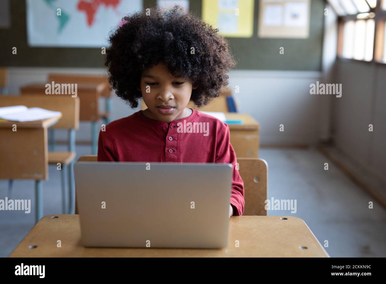 Boy using laptop while sitting on his desk in class at school Stock Photo