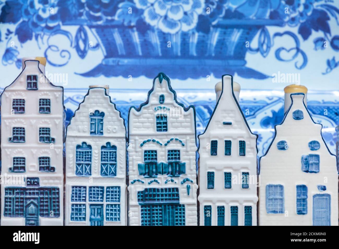 Row of Dutch Delft blue souvenir houses with an antique plate in the background Stock Photo