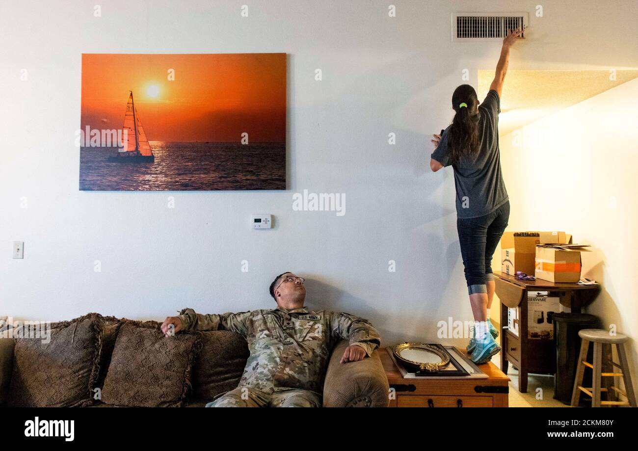 Leanne Bell, 39, checks the air quality of a vent as her husband, Spc.  Tevin Mosley, 26, looks on while waiting for a maintenance crew to arrive  at the army base housing