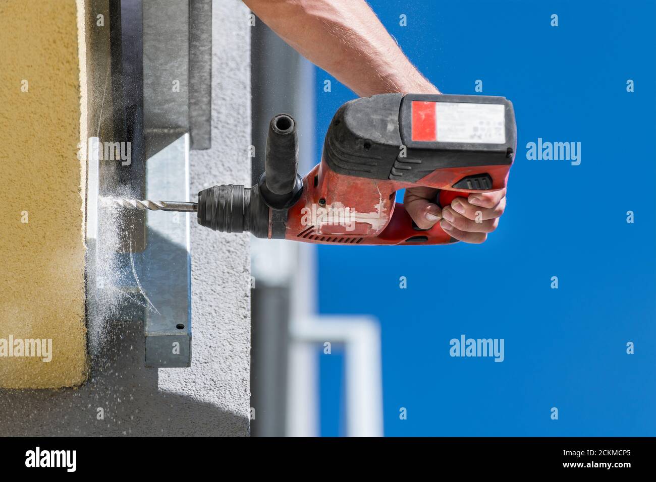 Working power hammer drill. Anchoring a steel construction. Fixing  into building masonry. Hand holding cordless drilling machine. Falling dust detail. Stock Photo