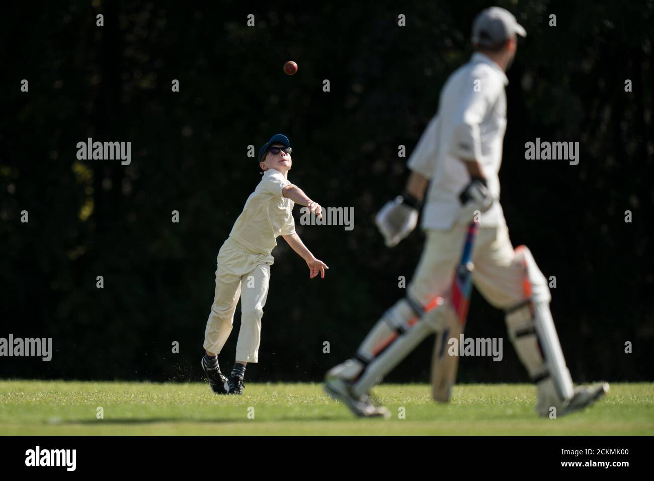 Young boy throwing cricket ball during village cricket match for all ages. Stock Photo