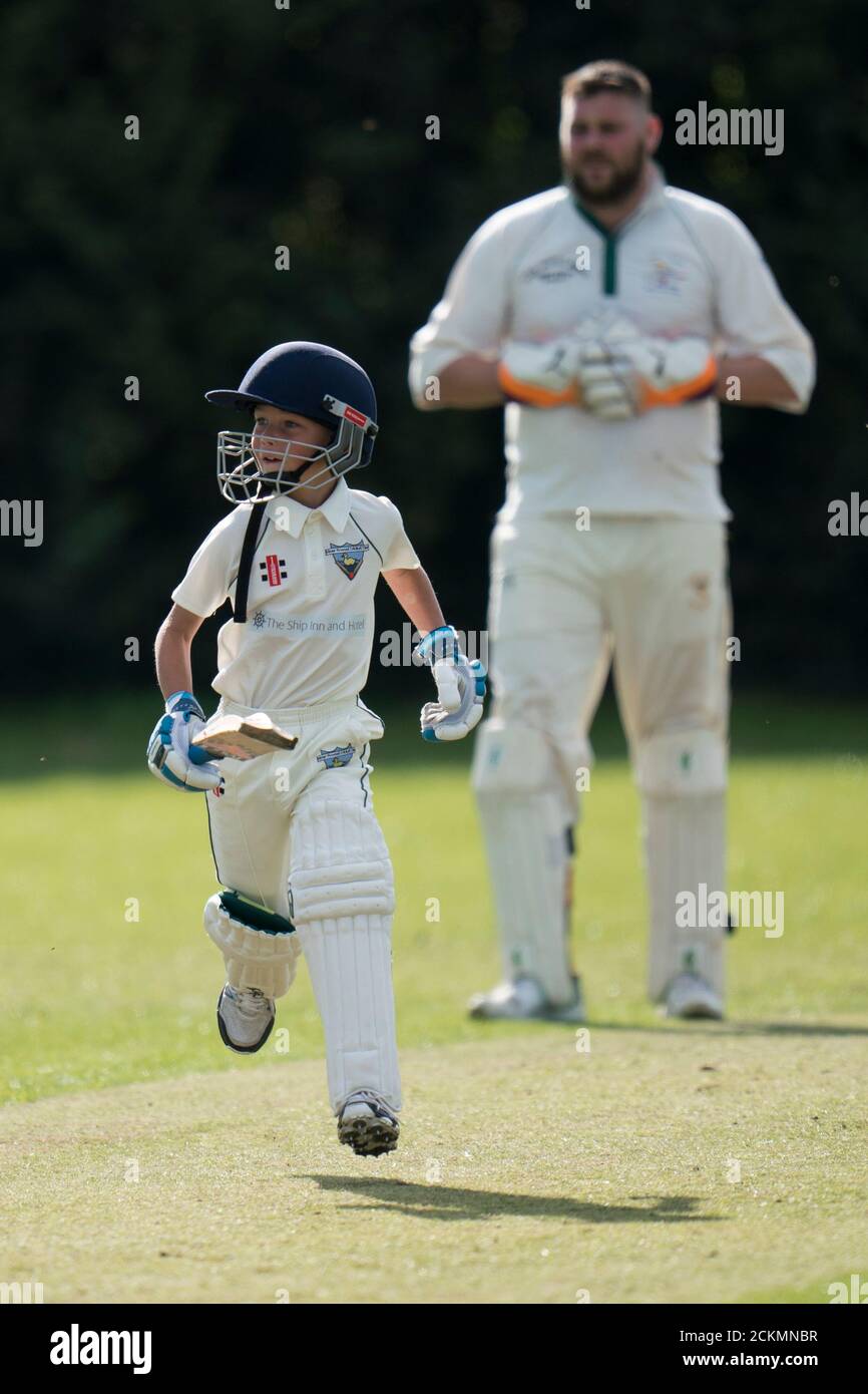 Young boy making runs during village cricket match for all ages. Stock Photo